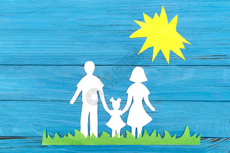 一个家庭的纸剪影站在阳光下的绿色草地上图片