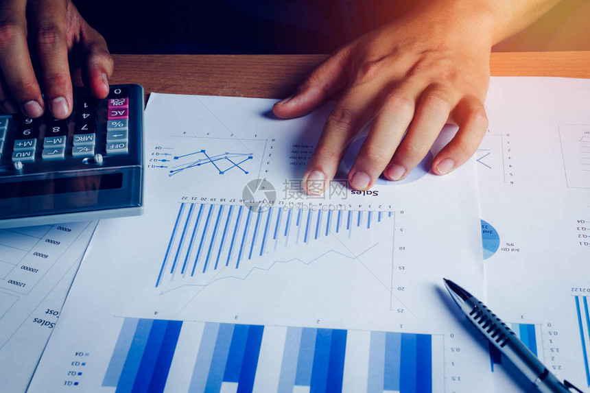 选择焦点手亚洲商人正在计算财务和会计与成长在家庭办公室的木桌上的纸质图表桌子上的钢笔计算器图形文件经济图片
