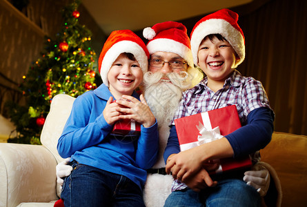 喜悦的男孩拿着礼物与圣诞老图片