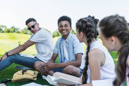 多种族多民族青少年学生群体在公园一起学习时互相笑图片