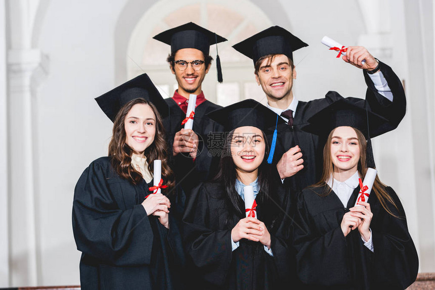 穿着毕业礼服的快乐学生群体笑着微图片