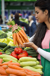 在市场上买蔬菜的年轻女人图片