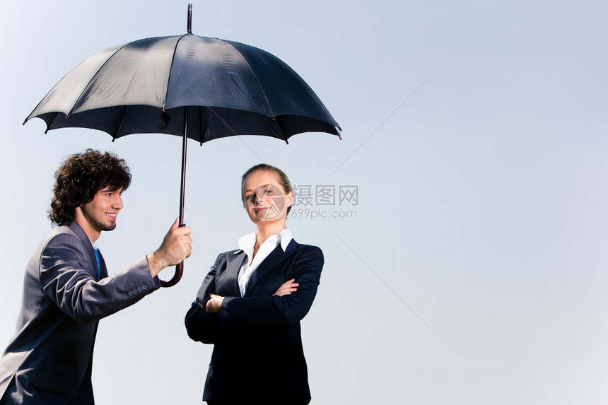 充满自信的商人持有伞和仰望背景中的女形象图片