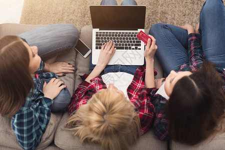 三个女孩用信卡和笔记本电脑在网上购物图片