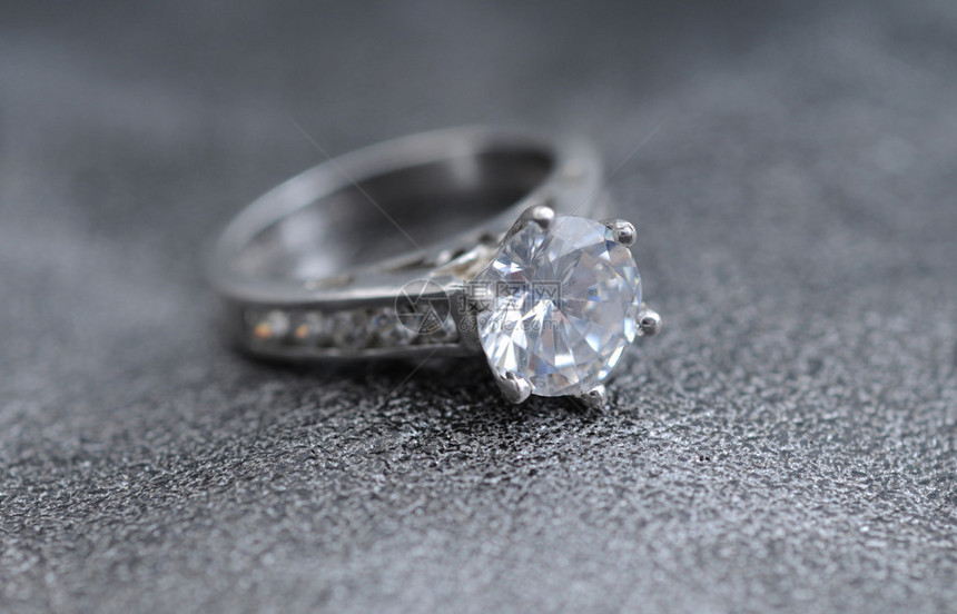优雅的灰色皮革背景上的钻石戒指图片