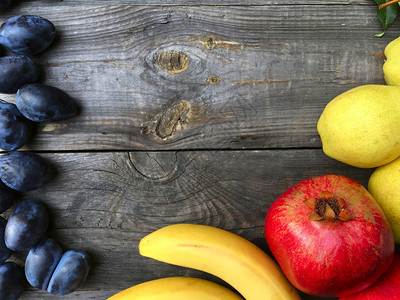 石榴梨香蕉和老木灰色背景的李子图片