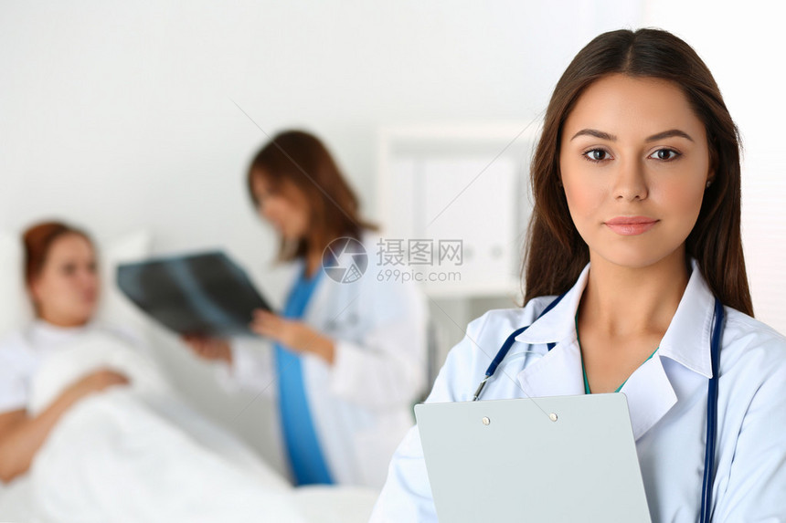 美丽的女医生在躺床上和外伤科医生交流的病人面前看着相机放射学或创伤学医概念医图片