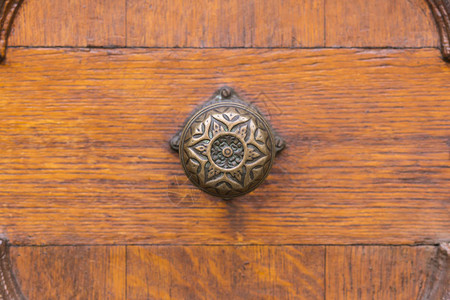 近距离接近一个复杂的圆铜门把手雕刻的木制门上有图片