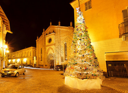 意大利阿尔巴晚间在旧教堂前的小广场上用塑料瓶制成的彩色圣诞树图片