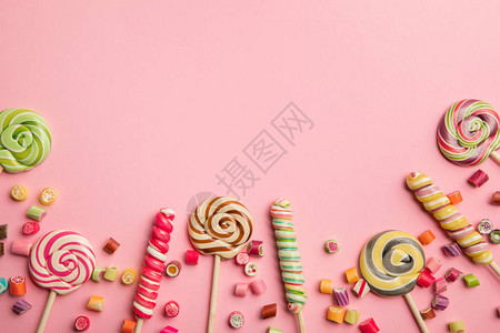 木棍和粉红色底糖果上方的多彩鲜图片