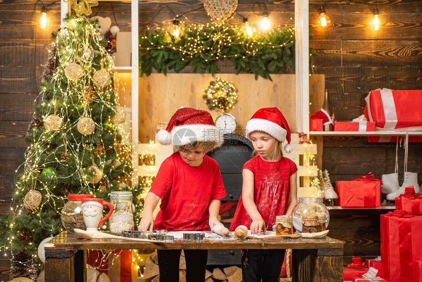 戴着圣诞帽的可爱孩子为家人准备节日晚餐两个戴着圣诞帽的可爱男孩两个戴着圣诞帽和围裙的孩子一起图片