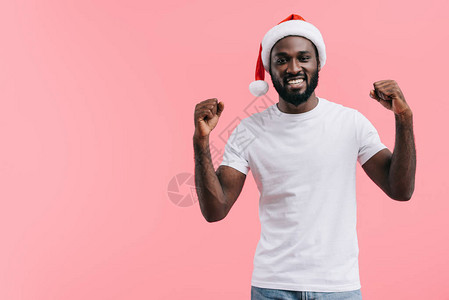 快乐的非洲美国人在圣诞节帽子上举起手来孤图片