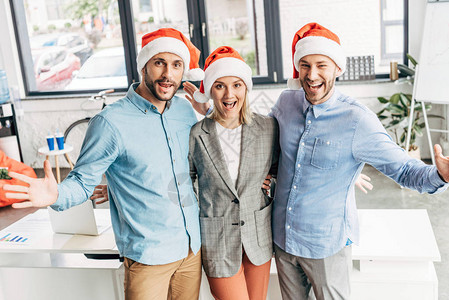 穿着圣诞老人帽子的年轻商业团队在办公图片