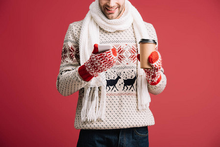 穿着冬季毛衣围巾帽子和手套的男子在使用智能手机时拿着咖啡走的剪影图片