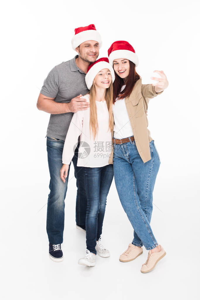 在圣塔帽中幸福的家庭用智能手机自拍图片