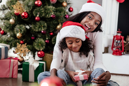 快乐的非洲美国女人和女儿在家里新年和圣诞节概念上戴着圣克拉图片