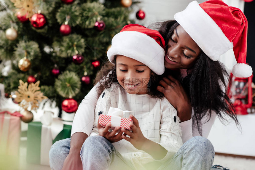 快乐的非洲美国女人和女儿在家里新年和圣诞节概念上戴着圣克拉图片