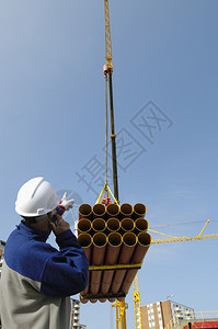 建筑工人引导重型起重机管道负荷建图片