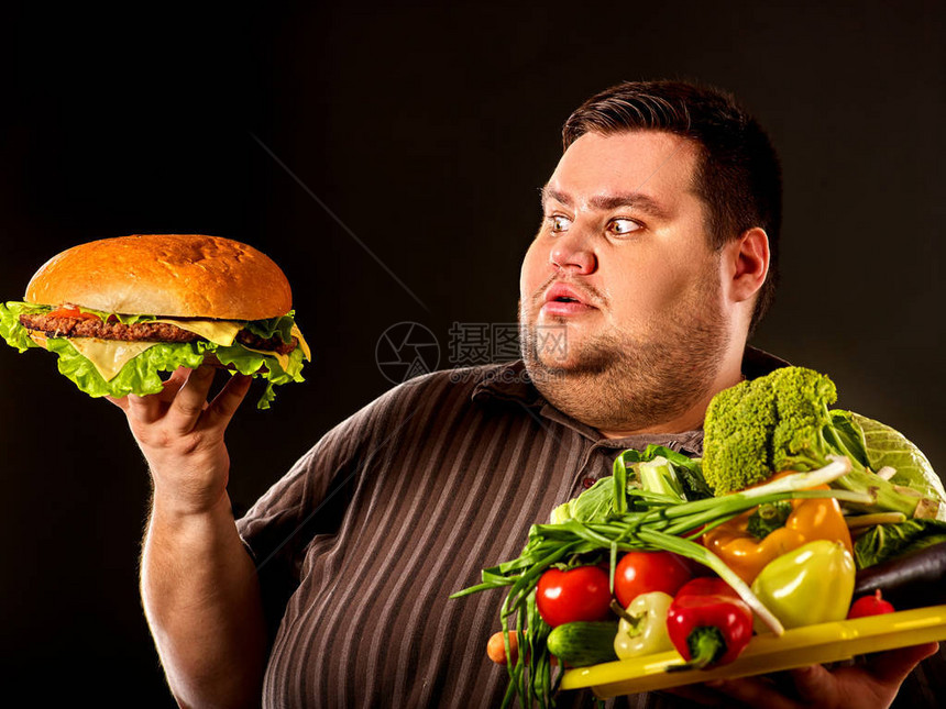 在健康和不健康的食物之间做出选择的节食胖子超重男与汉堡包健康有害营图片