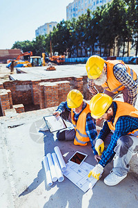 3名硬干工建筑工人坐在建筑工地的混凝土上图片