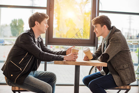 两个年轻人坐在咖啡厅里喝着咖啡聊图片