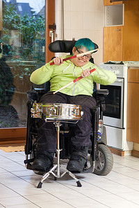 坐在多功能轮椅和打鼓的幼小脑图片