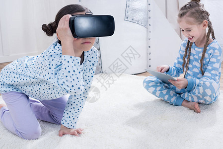 家庭地毯上坐着虚拟现实头耳机和数字平图片