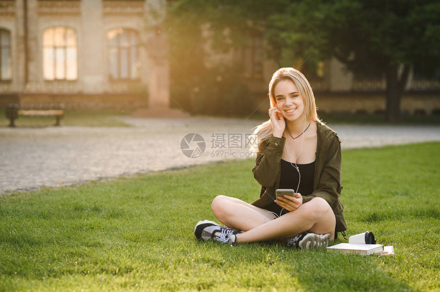 微笑的女学生坐在校园院子的草地上图片