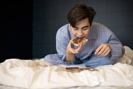 青少年男孩在床上吃饭的肖像图片
