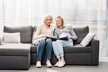 年轻孕妇与母亲在灰色沙发的图片