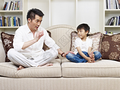 父亲和儿子在家里沙发上聊天图片