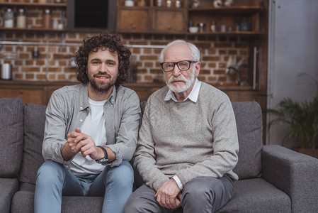 成年儿子和年长父亲坐在沙发上在图片
