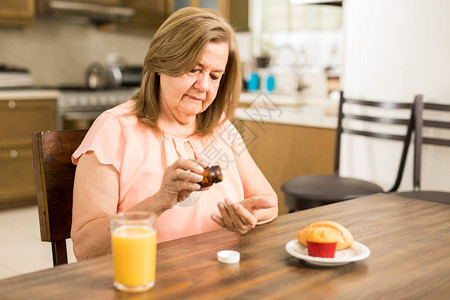 美丽的退休老太婆在家厨房吃饭时用早餐吃图片
