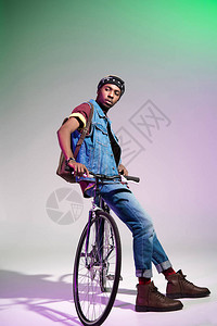 时尚的年轻非洲男子坐在自行车上仰图片