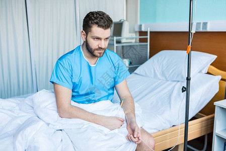 生病的留胡子男坐在医院床上图片