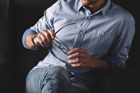穿着衬衫的男人坐在扶手椅上拿着眼镜的剪影背景图片