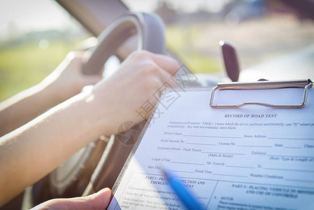 机动车驾照证填满驾照驶证检验表的考员与她的学生坐背景