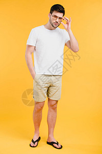穿着短裤和人字拖的英俊年轻人调整太阳镜图片