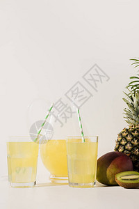 带吸管的玻璃杯和带果汁和新鲜热带水果图片