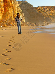 在葡萄牙萨格里斯附近的Tonel海滩上行走的年轻女子图片