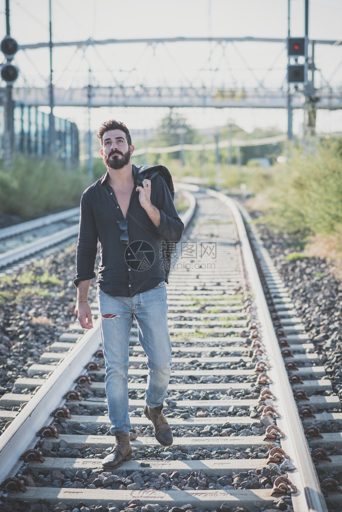 在铁路上行走的年轻英俊有魅力的长着图片