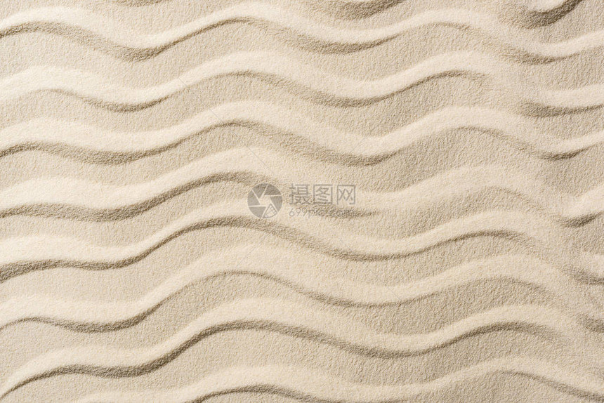 带沙子和平滑波浪的纹理背景的顶视图图片