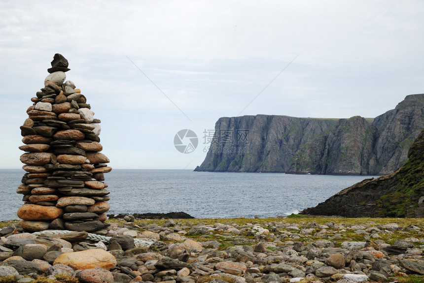 里程碑由前景中的鹅卵石制成背景中有一个黑暗的悬崖这是欧洲最北端的海角在北极阴云密布的天空下图片