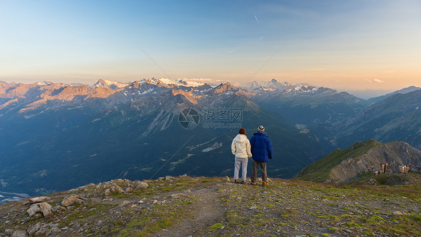情侣手拉观看日落时阿尔卑斯山的壮丽全景图片