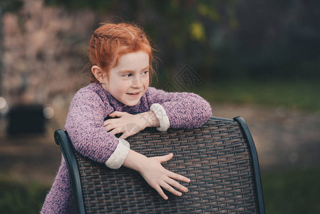 小女孩在后院坐在椅子旁边时向图片