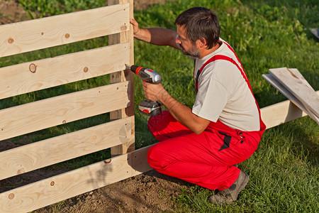 建造木栅栏的人用螺丝固定木板高清图片