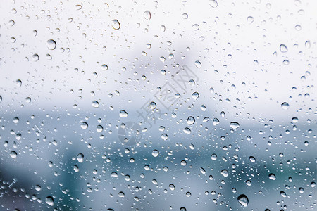 雨季在湿窗玻璃窗格表面上的雨滴抽象背景多云环境下室外模糊城市雨背景图片