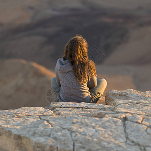 以色列内盖夫沙漠马赫特什拉蒙沙漠中坐在岩石背景图片