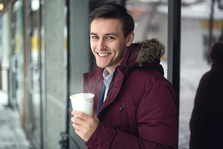 身穿西装和冬衣的年轻商人在寒冷街道喝热咖啡脸上满图片