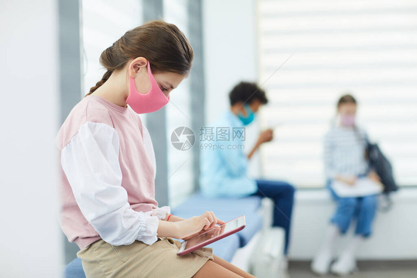 身着粉色面罩坐在学校医疗室和复印空间的Quque中图片